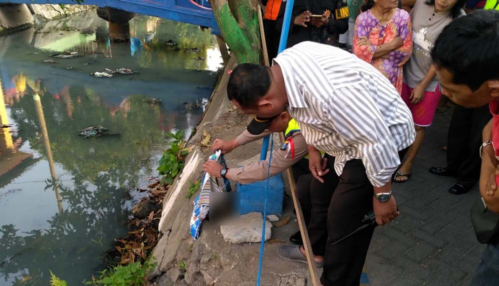 Petugas mengevakuasi jasad bayi di sungai dangkal Jalan Karang Menjangan 1B Surabaya, Kamis (11/10/2018).