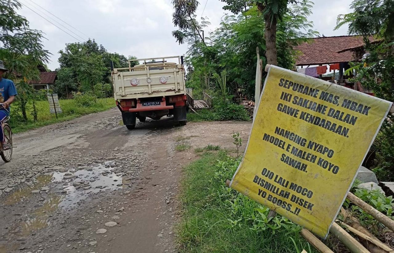 Salah satu banner berisi tulisan satire yang terpasang di jalan rusak di Ponorogo