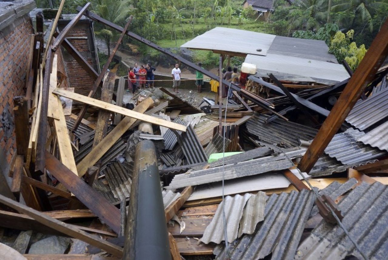 Warga melihat kondisi bangunan permukiman yang ambruk tertimpa tiang listrik akibat longsor di Munjungan, Trenggalek, Jawa Timur. (Foto: Antara/Destyan Sujarwoko via Republika)