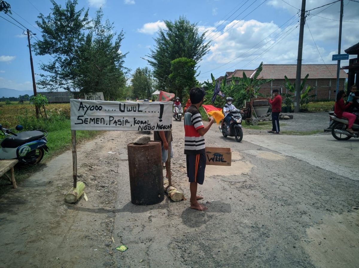 Warga mengumpulkan sumbangan untuk perbaikan jalan  rusak. (Foto: Mita Kusuma/jatimnow.com)