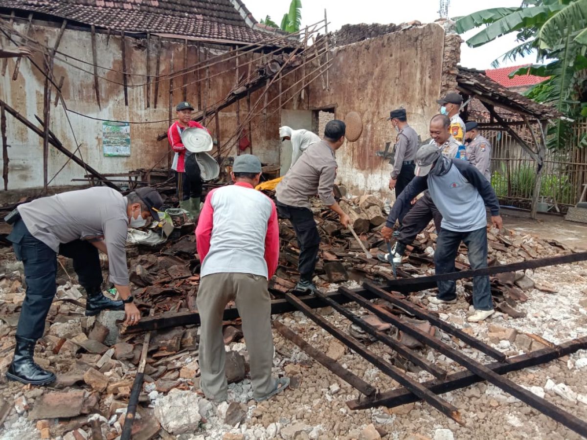 Anggota Polsek Takeran melaksanakan kerja bakti membersihkan material rumah yang roboh (Foto: Polsek Takeran/jatimnow.com)
