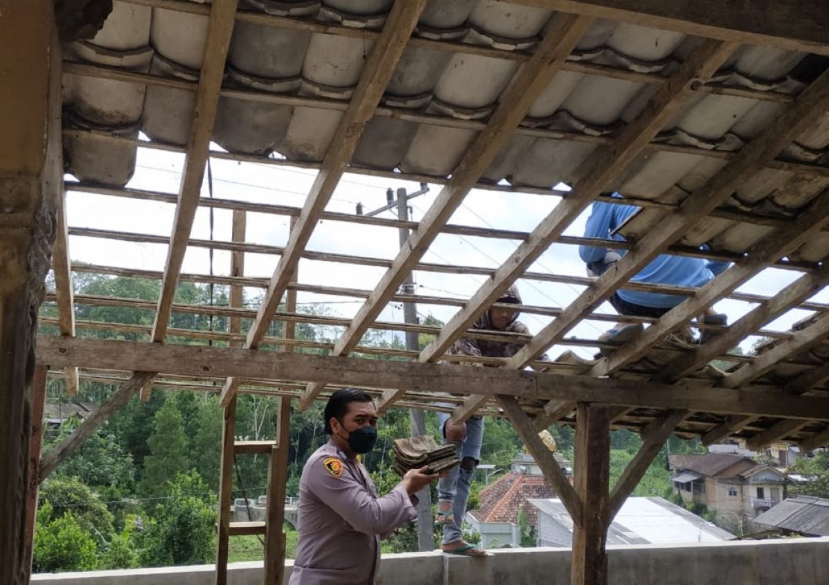 Polisi dan warga kerja bakti di rumah yang roboh kena hujan angin. (Foto: Polsek Ngrayun/jatimnow.com)