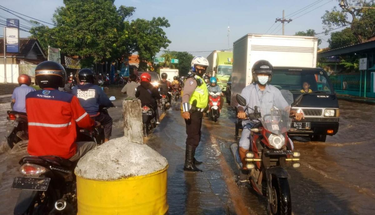 Petugas mengatur lalin di Raya Pasuruan-Probolinggo yang macet karena banjir. (Foto: Moch Rois/jatimnow.com)