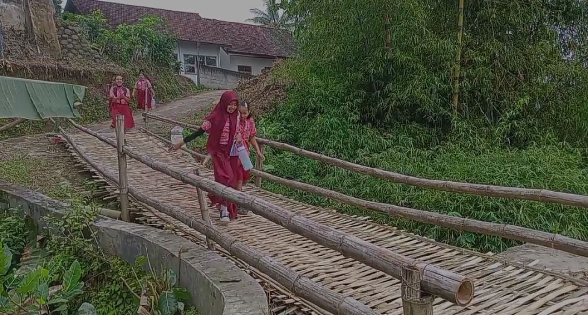 Siswa di Pohaman melintasi jembatan besek bambu yang rawan ambrol. (Foto: Mita Kusuma/jatimnow.com)