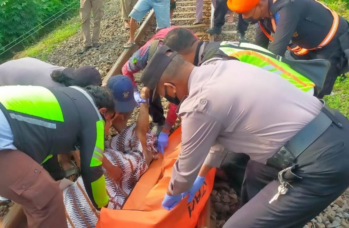 Petugas mengevakuasi jenazah kakek tersambar KA Komuter di Pasuruan. (Foto: Polsek Gempol/jatimnow.com)