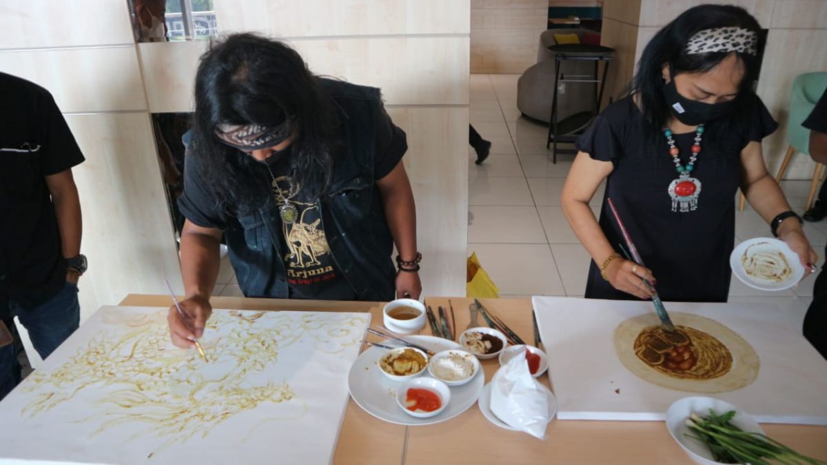 Amat Mulyono (kiri) saat melukis menggunakan cat bahan dapur di Midtown Residence Surabaya (Foto: Fajar Mujianto/jatimnow.com)
