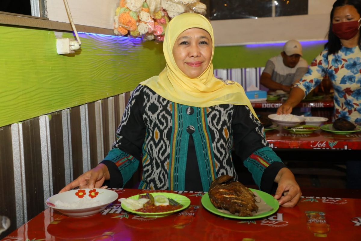 Gubernur Jatim Khofifah Indar Parawansa menyantap ikan asap khas Desa Tamansari, Kecamatan Dringu, Probolinggo.(Foto: Humas Pemprov Jatim)