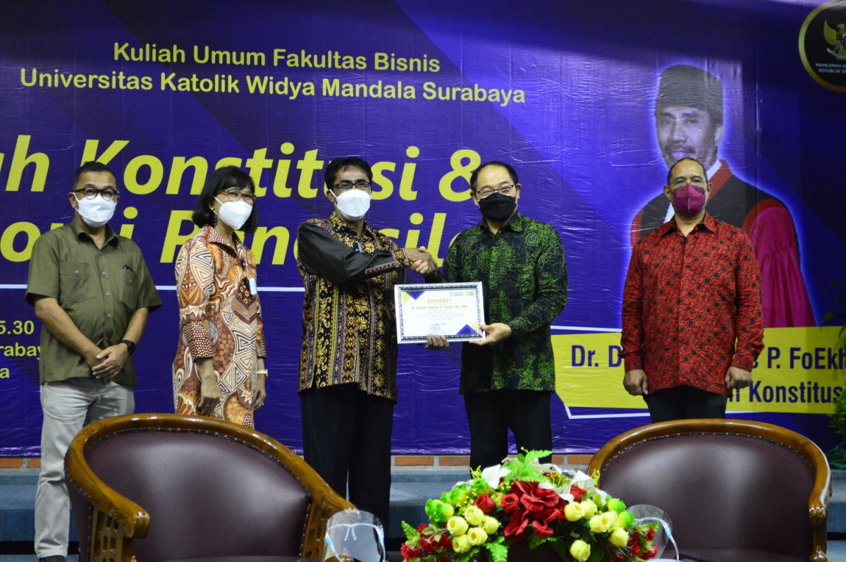 Hakim MK Daniel Yusmic P. Foekh menerima sertifikat penghargaan dari Rektor UKWMS Kuncoro Foe.(Foto: Humas UKWMS)