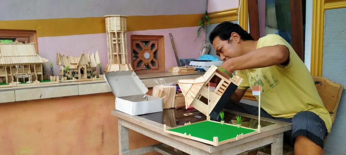 Solikin merakit miniatur berbahan stik es krim saat ditemui di rumahnya. (Foto-foto: Elok Aprianto/jatimnow.com)