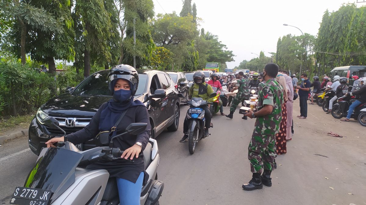 Pembagian takjil kepada para pengguna jalan di Jembatan Ngaglik oleh Kodim 0812 Lamongan (Foto: Adyad Ammy Iffansah/jatimnow.com)