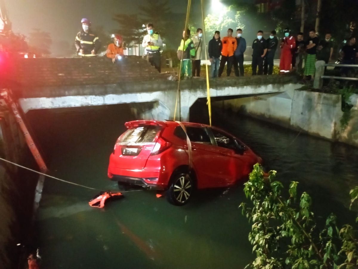 Mobil Honda Jazz merah yang nyemplung ke sungai saat dievakuasi petugas. (Foto: info kedaruratan 112 Surabaya)