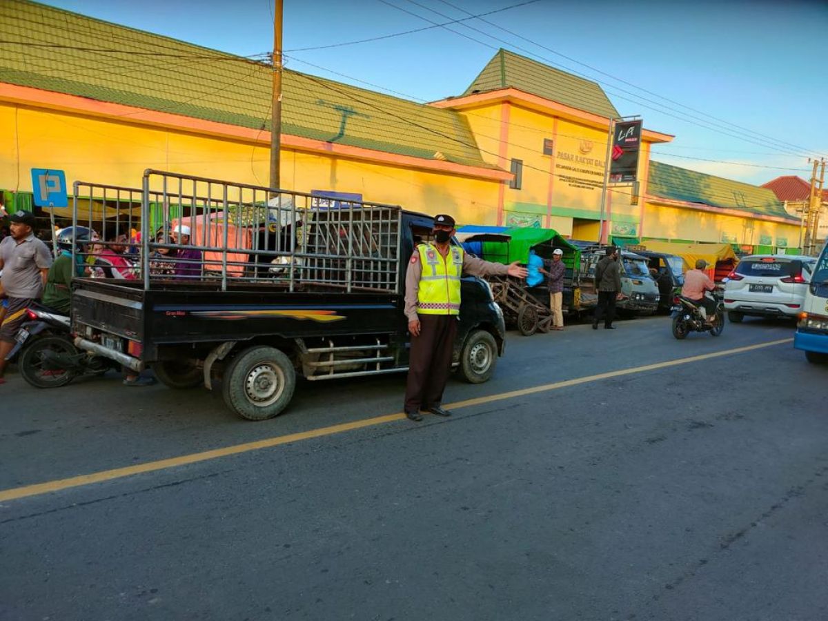 Polisi melakukan pengalihan jalur di tengah kemacetan di lokasi pasar tumpah, Kecamatan Galis, Bangkalan.(Foto: Fathor Rahman)