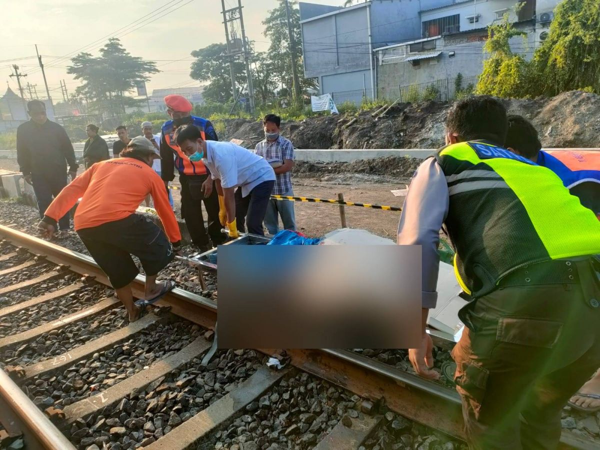 Petugas saat mengevakuasi jenazah pria tanpa identitas dari perlintasan KA di Desa Sidodadi. (Foto: Polsek Taman/jatimnow.com)
