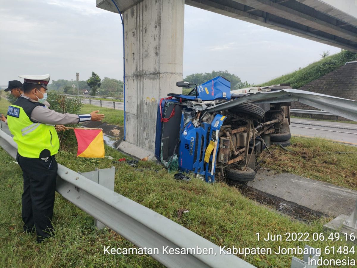 Polisi dan petugas tol saat melakukan evakuasi truk tangki yang terguling usai menabrak gadril.(Foto: PJR Polda Jatim)