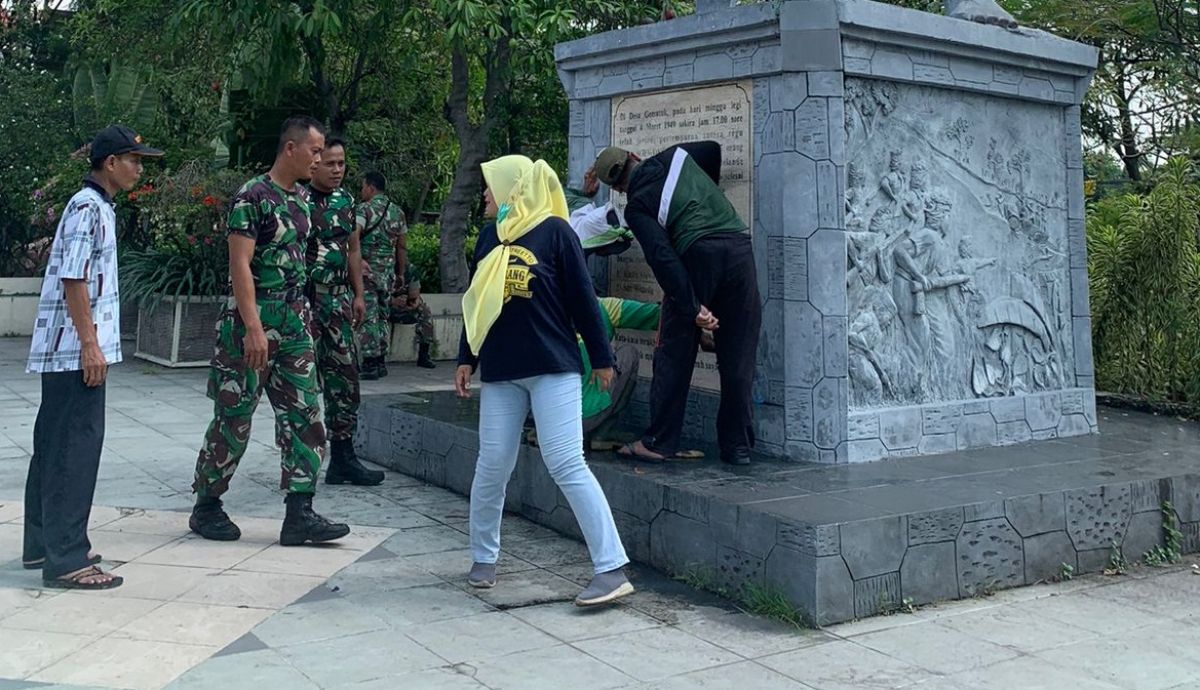 DLH dan Kodim 0812 Lamongan saat membersihkan vandalisme di patung Kadet Soewoko. (Foto: Adyad Ammy Iffansah)
