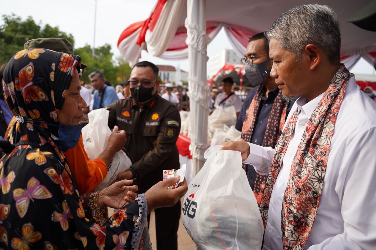 SVP of Supporting SIG, Muchamad Supriyadi (kanan), menyerahkan paket sembako murah kepada warga Rembang pada acara Pasar Murah dan Bazar UMKM BUMN di Alun-alun Rembang (Foto-foto: SIG for jatimnow.com)