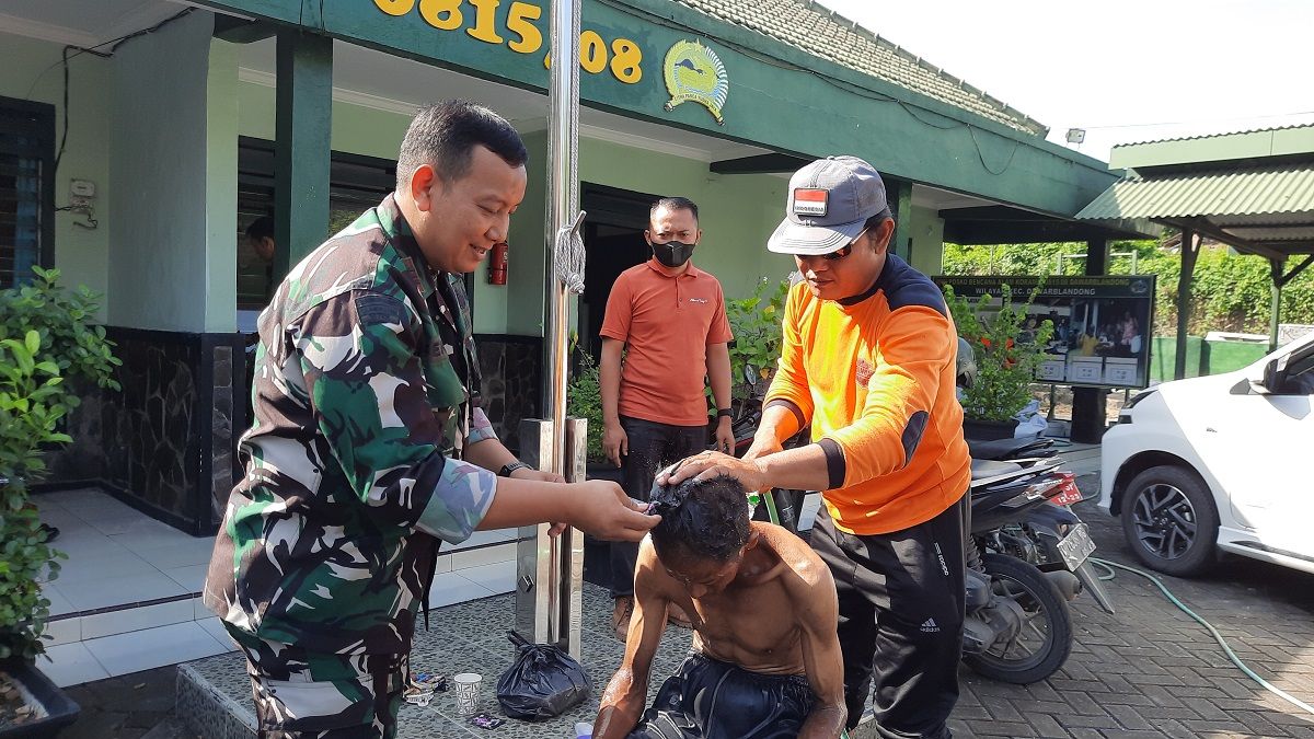 Danramil Dawarblandong, Kapten Inf Benny Irawan saat merawat warga penderita ODGJ. (Foto: Achmad Supriyadi/jatimnow.com)