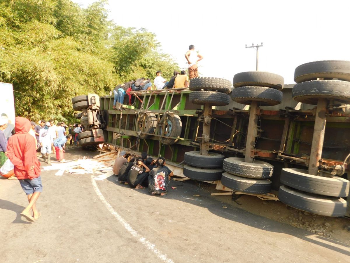 Truk trailer bermuatan triplek terguling dan timpa mobil di Kalisat, Jember. (Foto: Ambang/jatimnow.com)
