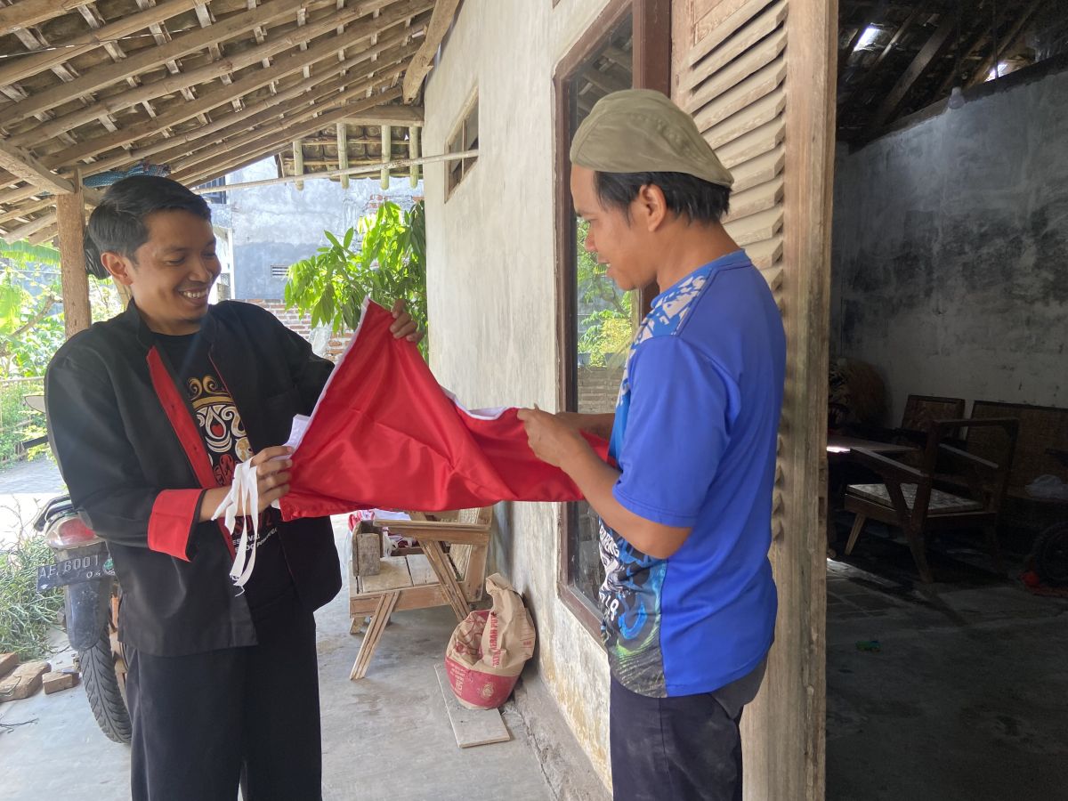 Aksi Tarmin saat membagikan bendera merah putih buatannya secara gratis. (Foto: Mita Kusuma/jatimnow.com)
