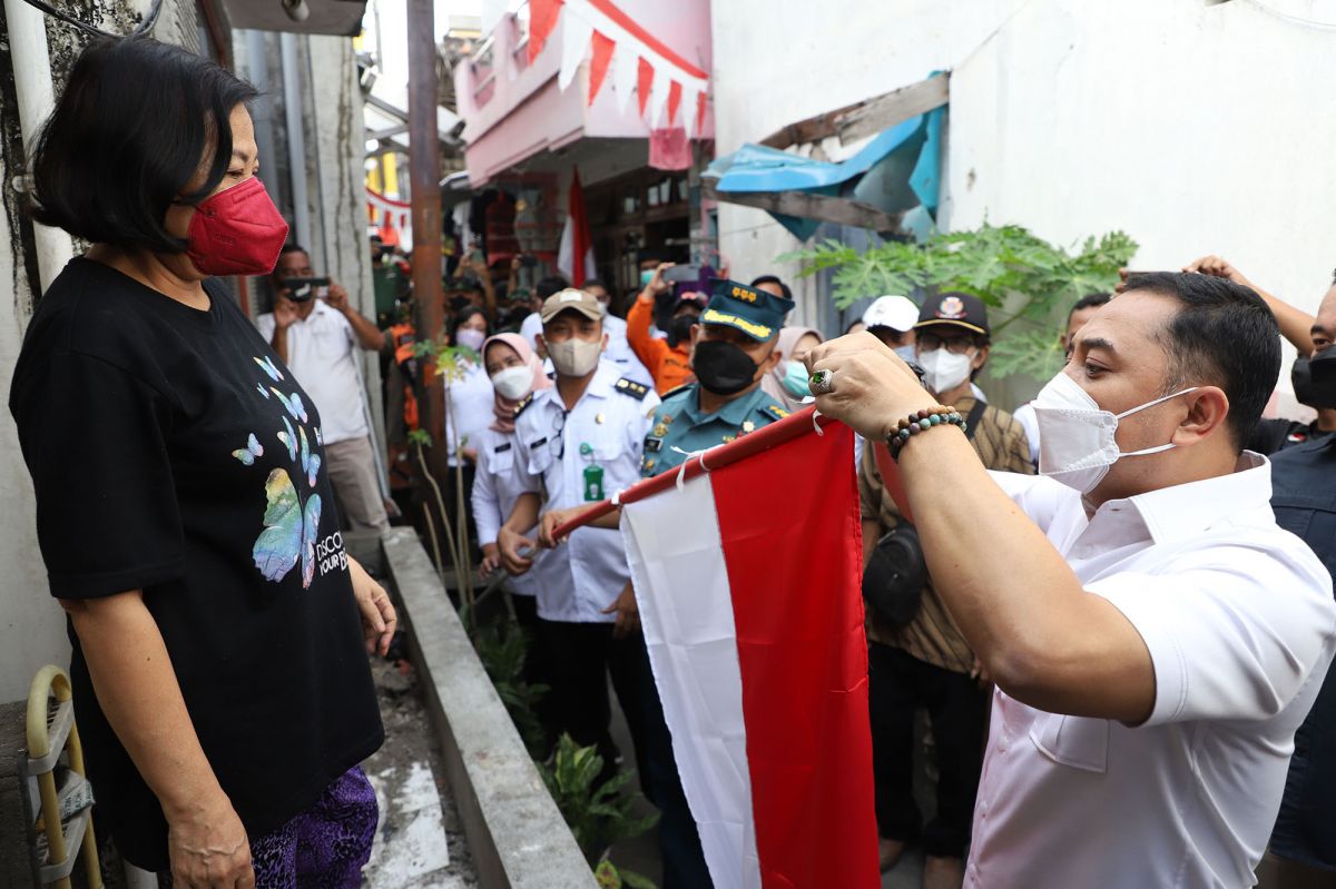 Cak Eri Cahyadi memasangkan bendera merah putih di depan rumah warga Tambaksari. (Foto: Humas Pemkot Surabaya/jatimnow.com)