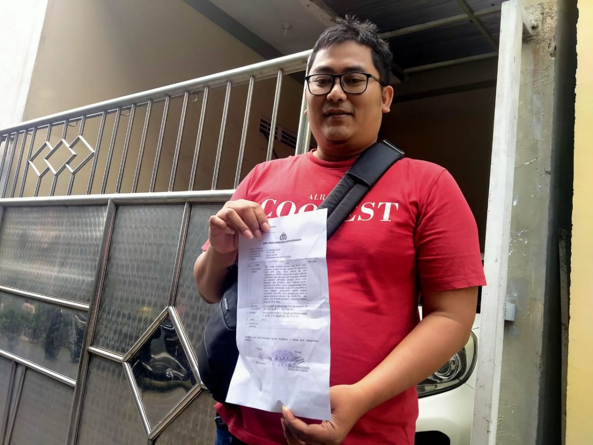 Suami korban menunjukan laporannya ke Polres Batu. (Foto: Galih Rakasiwi/jatimnow.com)