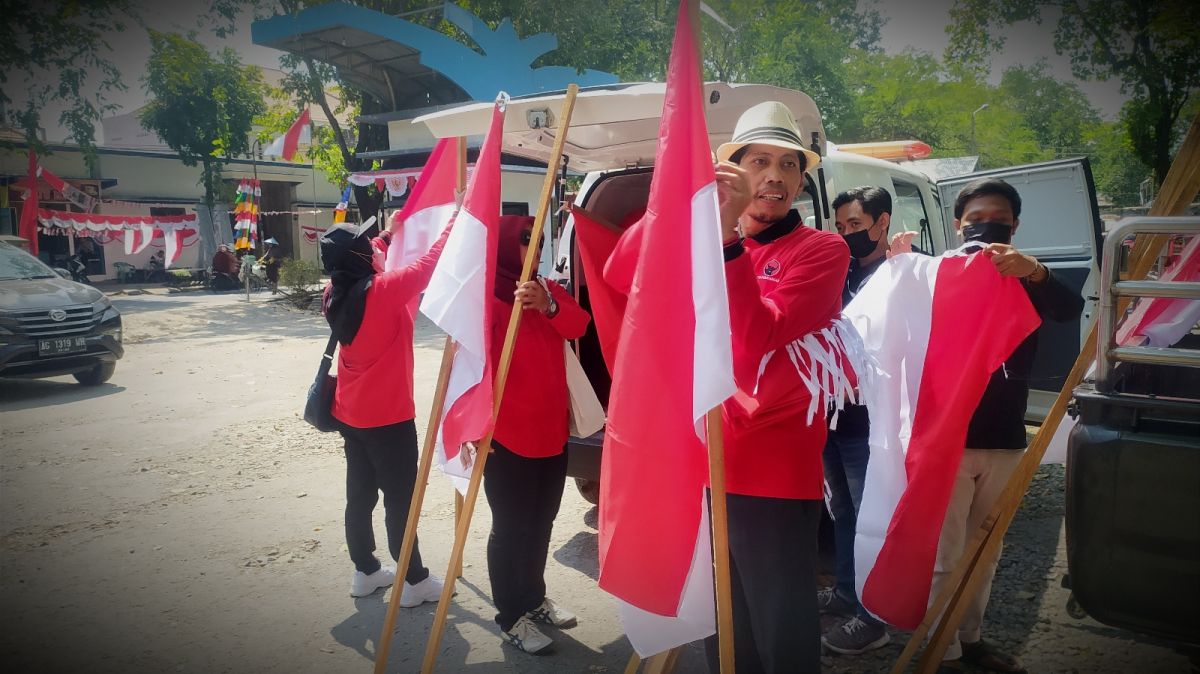 Ketua DPC PDIP Lamongan Husen saat melakukan aksi pasang Bendera Merah Putih di kawasan pasar burung.(Foto: Adyad Ammy Iffansah/jatimnow.com)