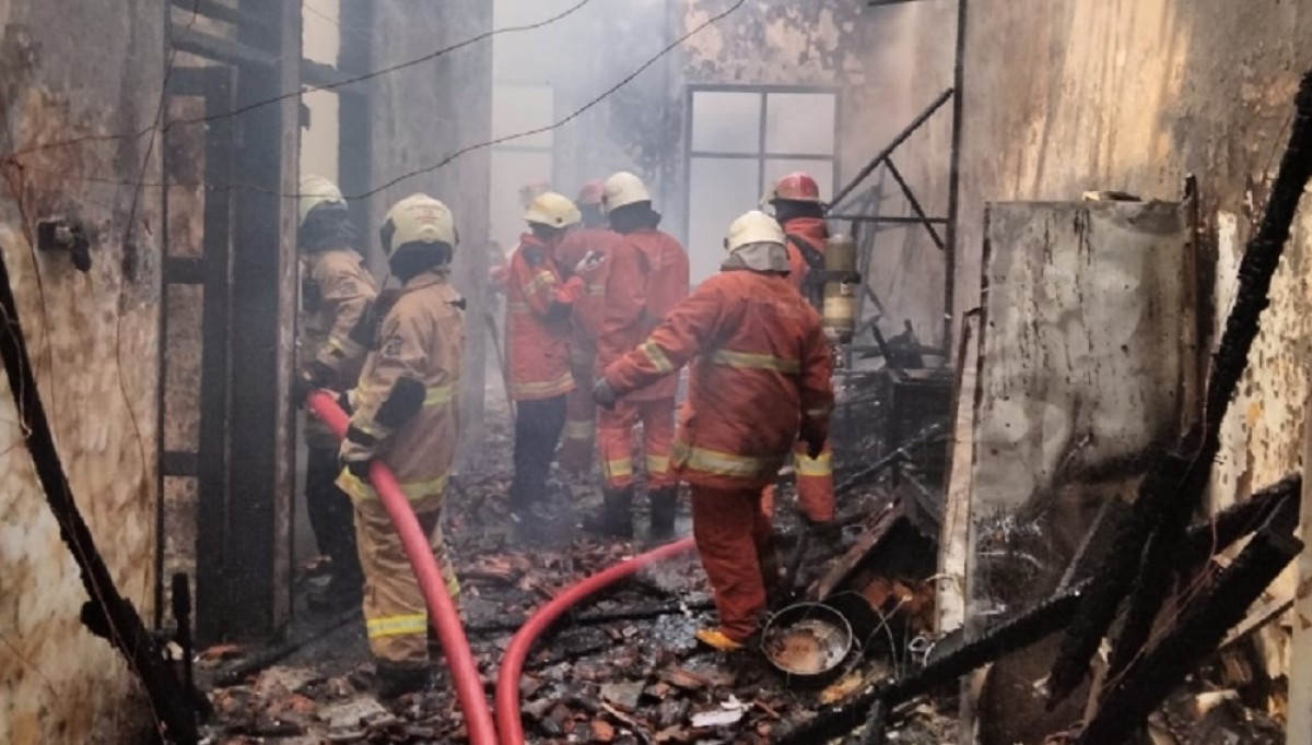 Petugas melakukan pembasahan di lokasi kebakaran. (Foto Info Kedaruratan 112 Surabaya)