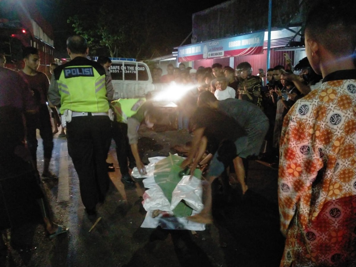 Polisi mengevakuasi jenazah pria tabrakkan diri ke truk di Jember. (Foto: Satlantas Polres Jember/jatimnow.com)