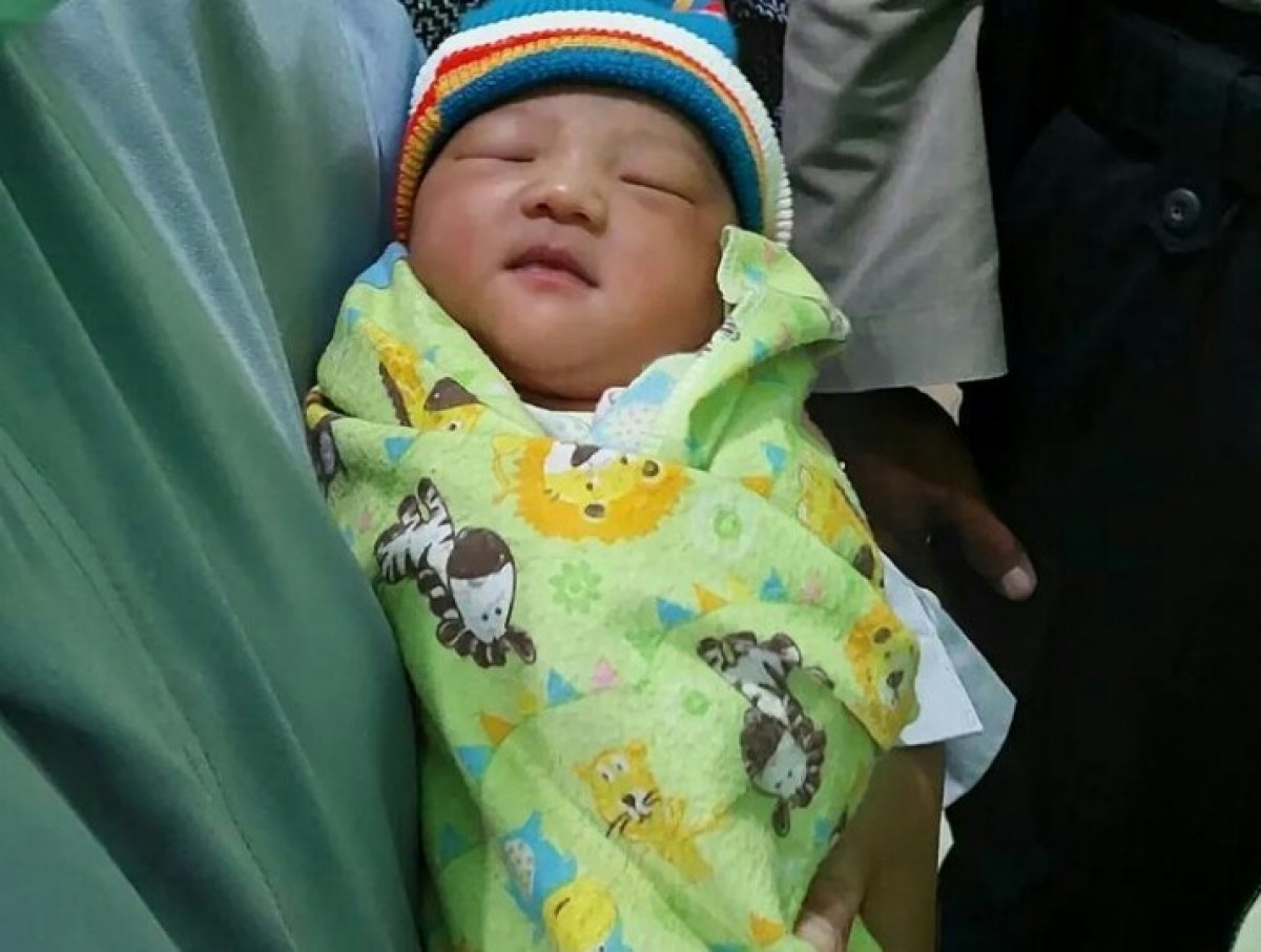 Bayi mungil yang terlelap dalam gendongan petugas puskesmas.(Foto: Misbahul Munir/jatimnow.com)