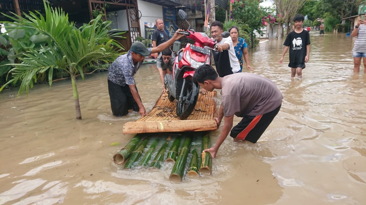 Warga Desa Ngadirenggo, Kecamatan Pogalan mengevakuasi motor dengan menggunakan rakit bambu. (Foto-foto: Bramanta Pamungkas/jatimnow.com)