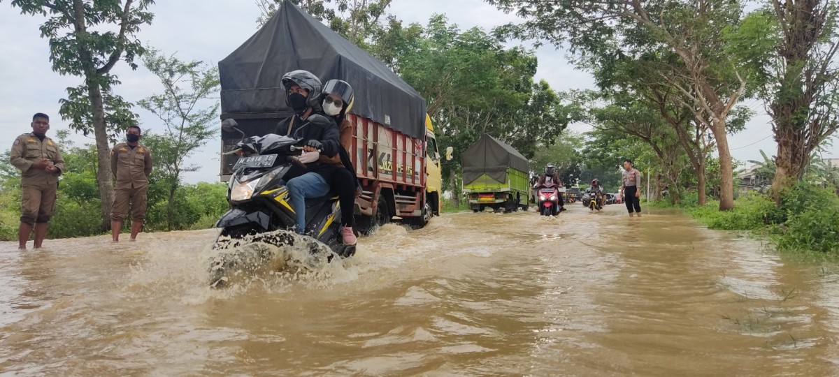 Air kiriman dari wilayah Utara menggenangi jalan di daerah perbatasan Kabupaten Bangkalan dan Sampang, Rabu (26/10/2022).(Foto: Fathor Rahman)
