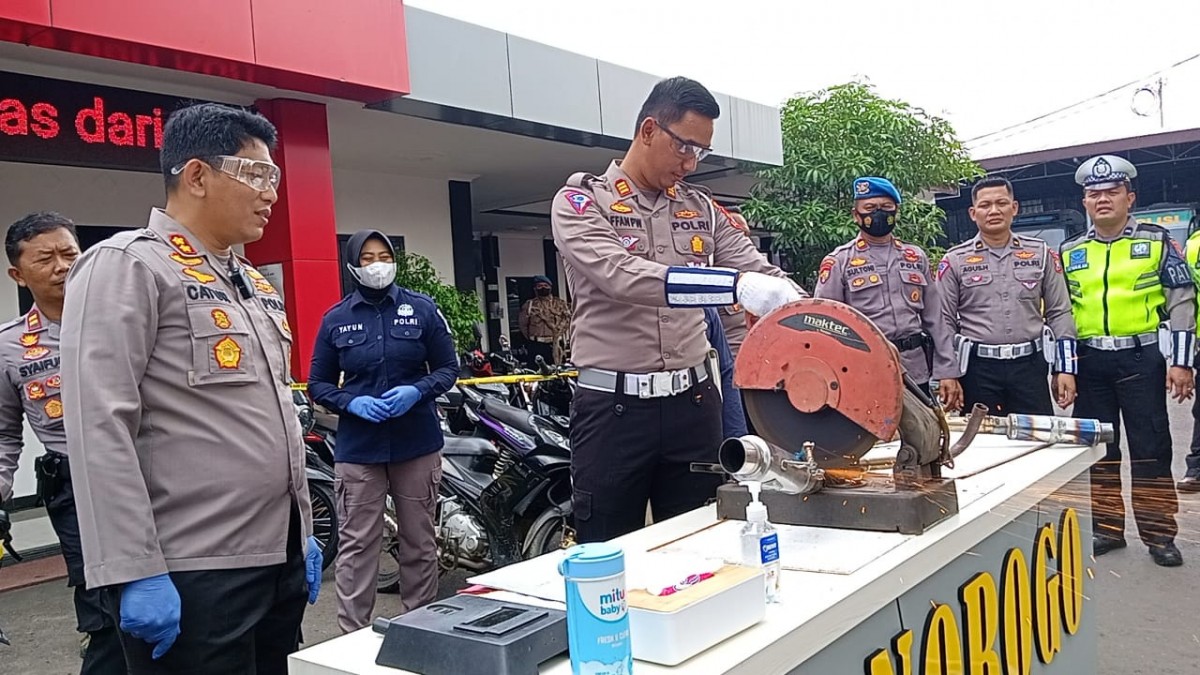 Kasatlantas Polres Ponorogo, AKP Affan Priyo Wicaksono sedang menggergaji salah satu knalpot brong. (Foto: Ahmad Fauzani/jatimnow.com)