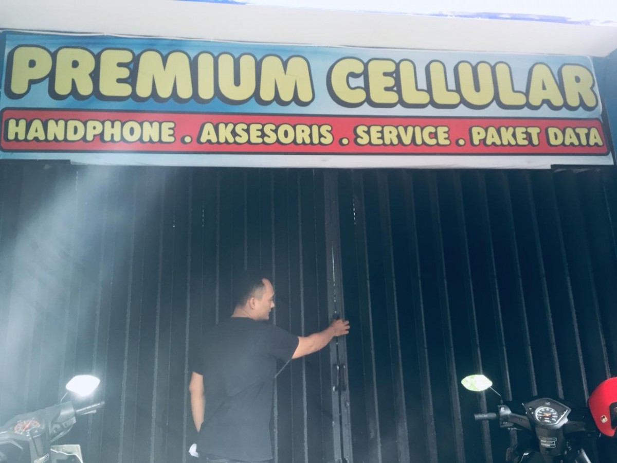 Henokh, pengawas konter menunjukkan gembok pintu harmonika yang dirusak dan tempat CCTV yang recodernya dicuri maling (Foto: Henokh for jatimnow.com)