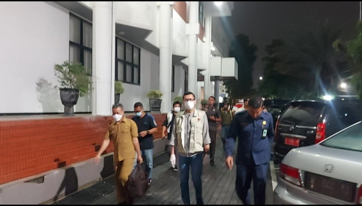 Petugas KPK bersama seorang pegawai ASN keluar dari pintu belakang Gedung DPRD Jatim. (foto: Ni'am Kurniawan/jatimnow.com)