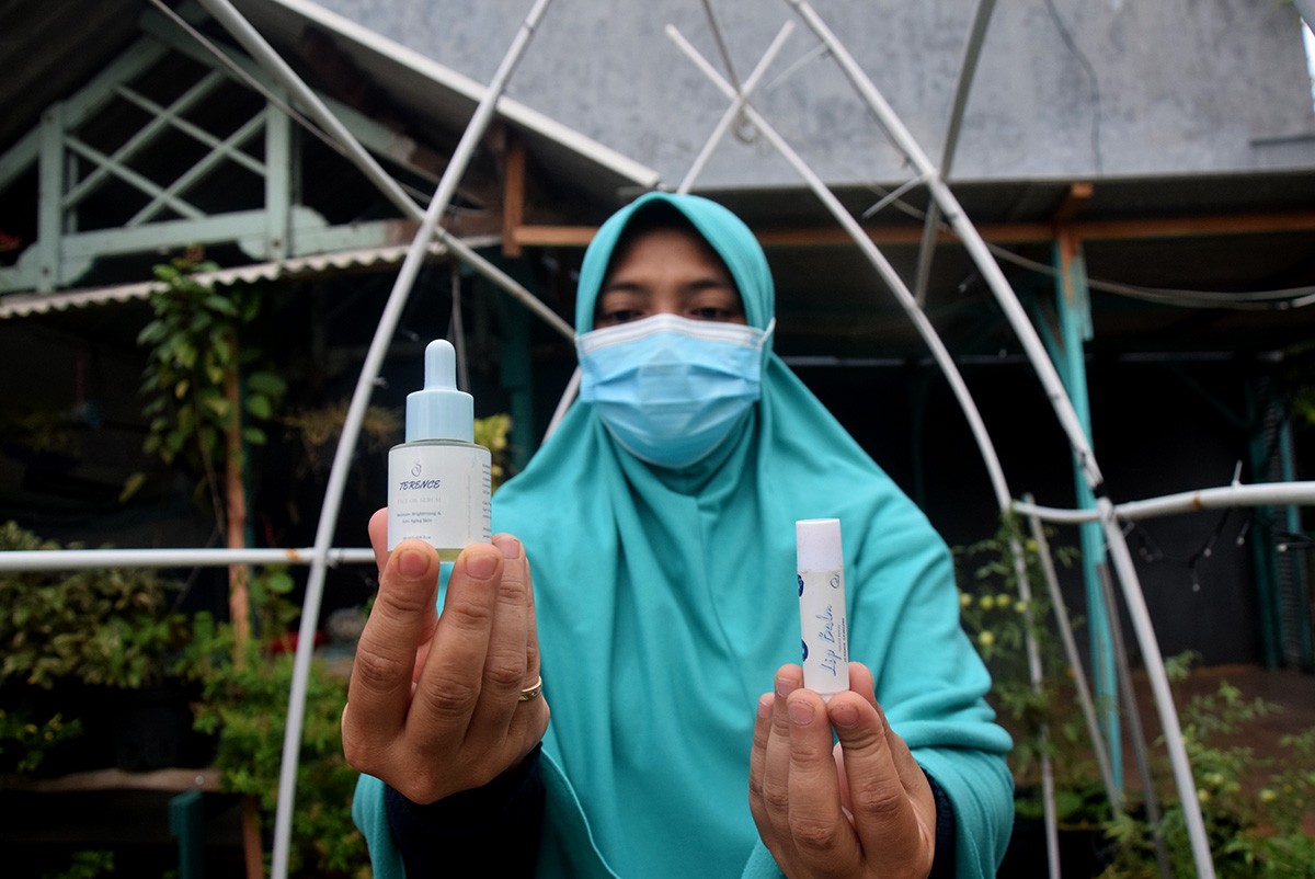 Warga medokan ayu menunjukkan lip balm dan face oil berbahan bunga telang. (foto: Rochman Arief/jatimnow.com)