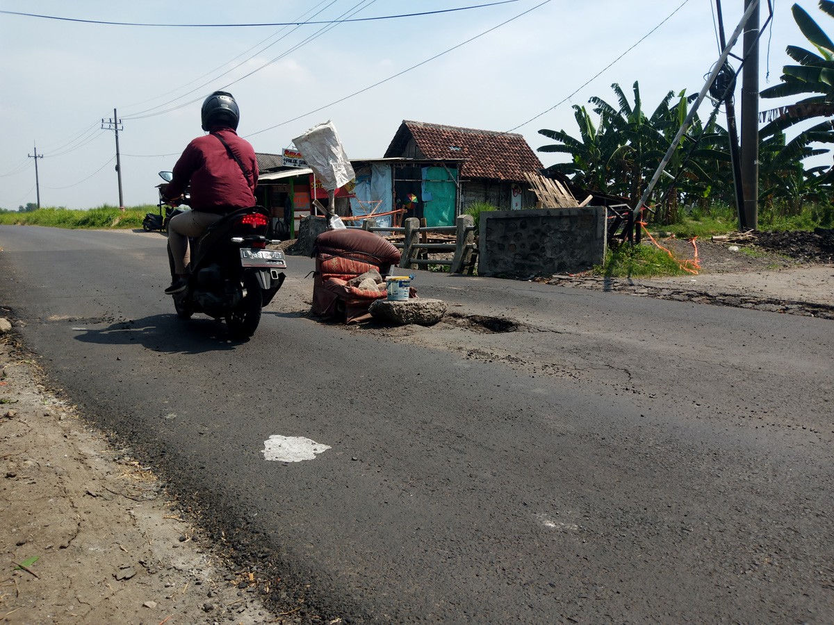 Kondisi jalan yang ambles dan dipasangi sofa bekas oleh warga. (foto: Zainul Fajar/jatimnow.com)