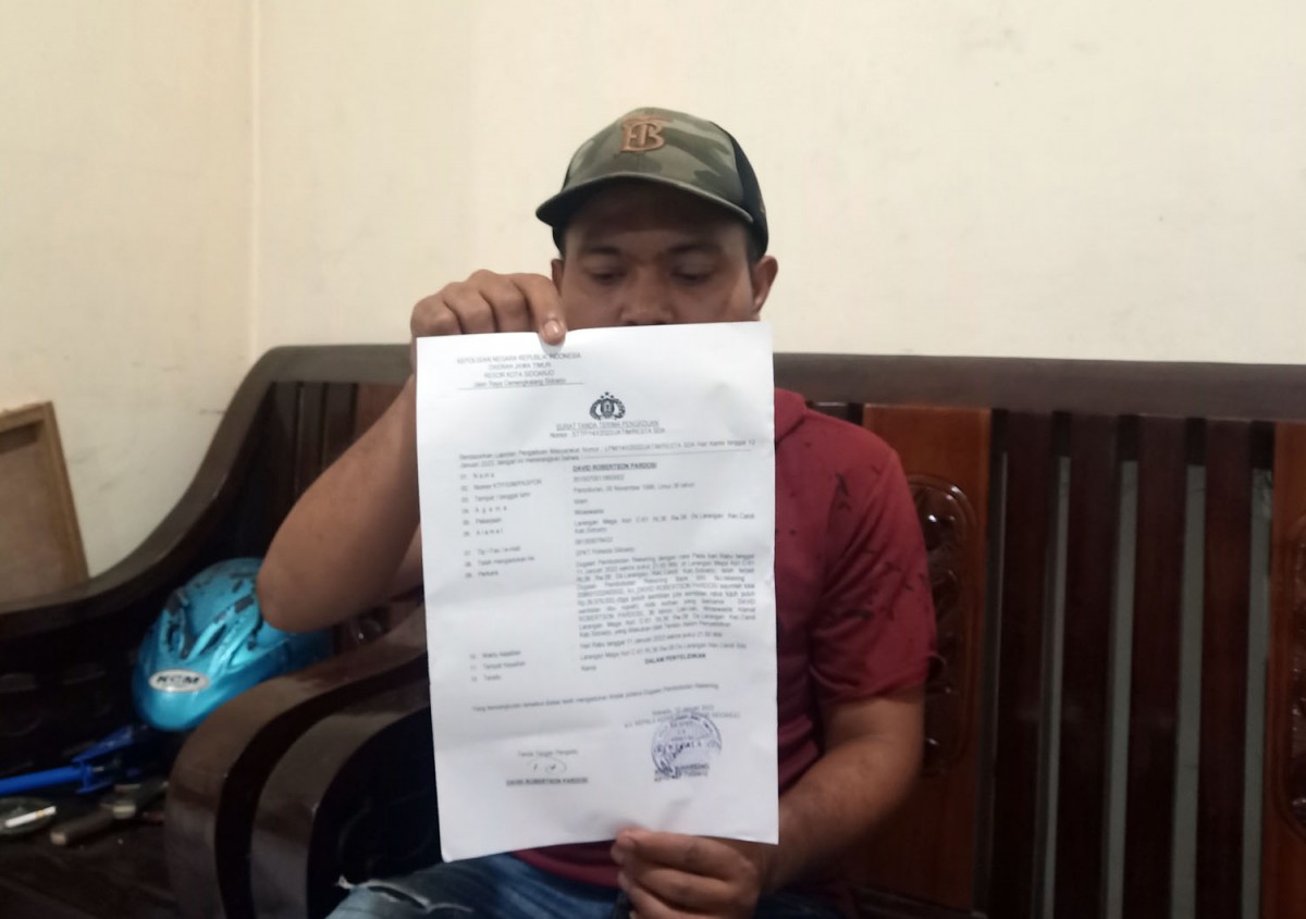 Korban saat menunjukkan surat laporan polisi yang dibuatnya (Foto: Zainul Fajar/jatimnow.com)