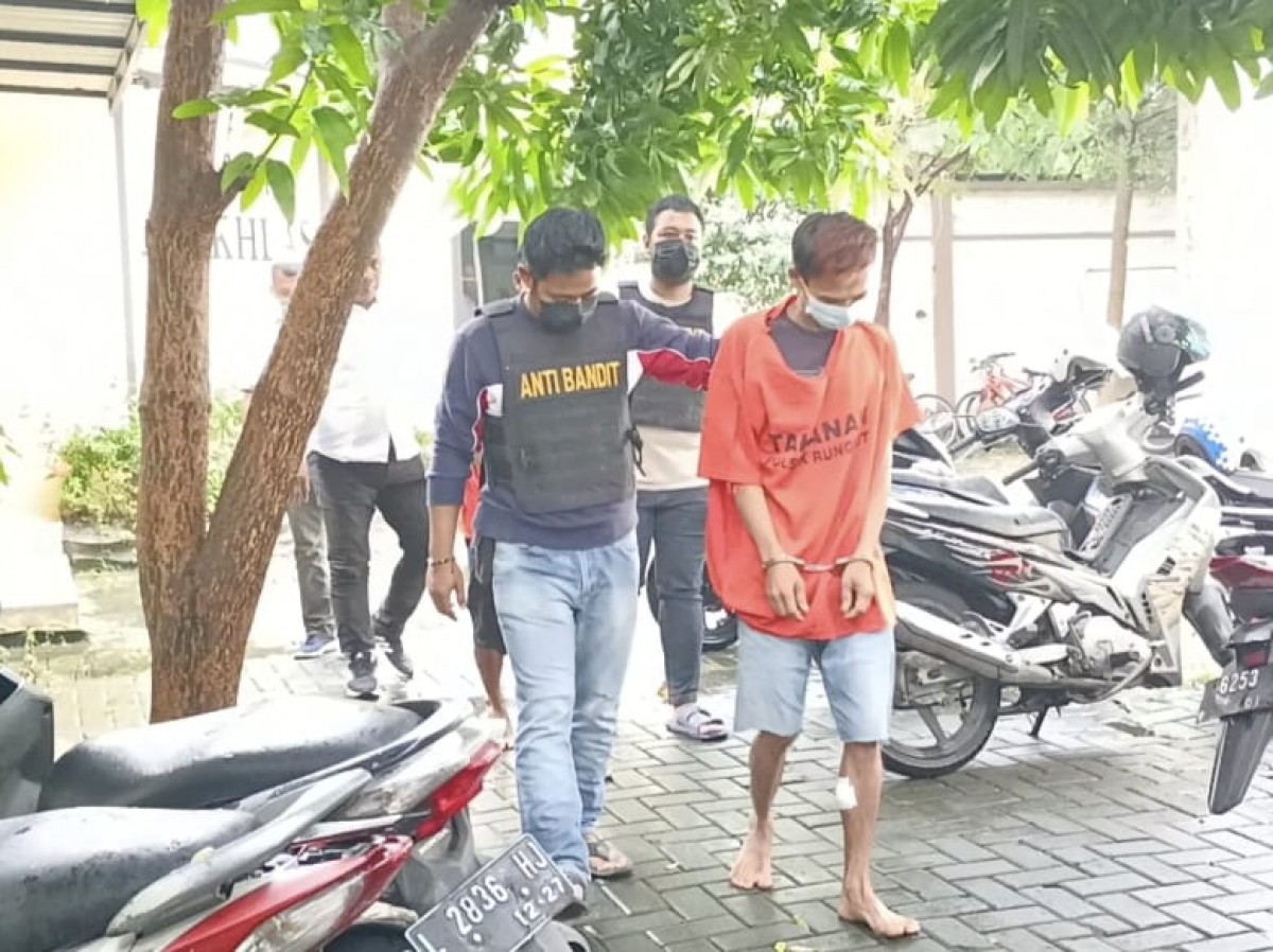 Salah satu perampok dibantu anggota Polsek Rungkut untuk berjalan setelah betis kirinya dilubangi timah panas. (foto: Zain Ahmad/jatimnow.com)