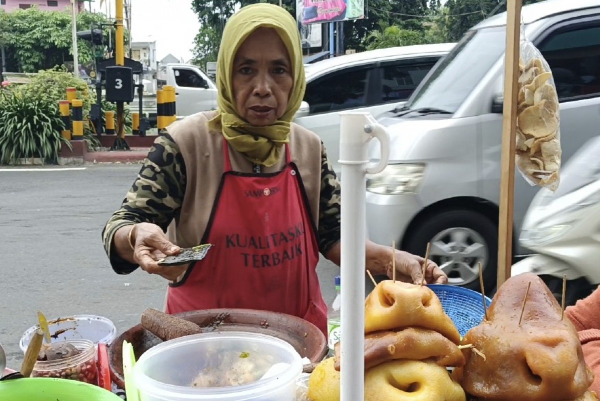 Saerah saat meracik bumbu rujak cingur untuk melayani pelanggannya. (foto-foto: Rama Indra Surya/jatimnow.com)