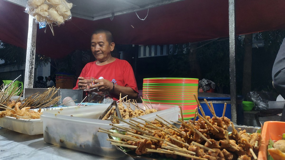 Cak Mis (baju merah) saat sibuk meladeni pengunjung. (Foto: Ni'am Kurniawan/jatimnow.com)