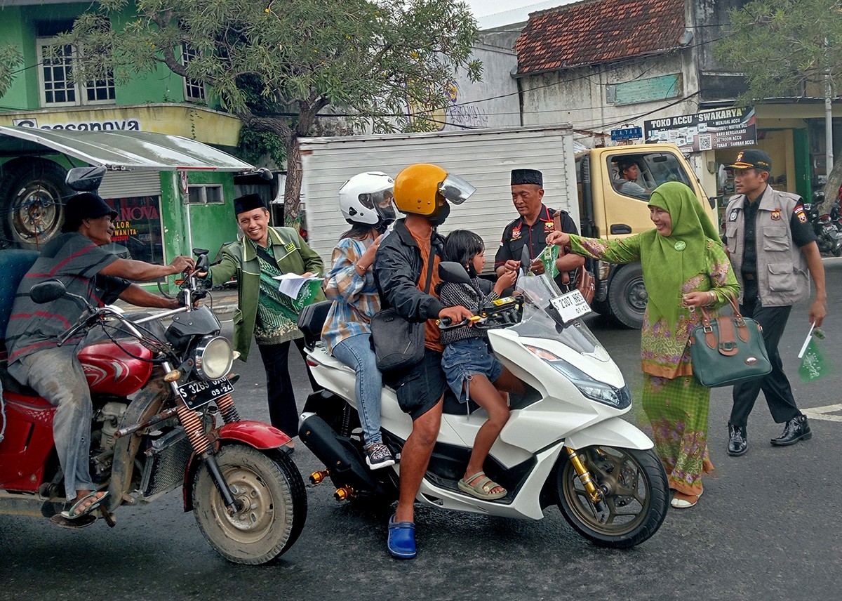 Anggota forum lintas agama dan organisasi kemasyarakatan di Jombang membagikan bendera NU ke pengguna jalan di bundaran ringin contong. (foto: Elok APrianto/jarimnow.com)
