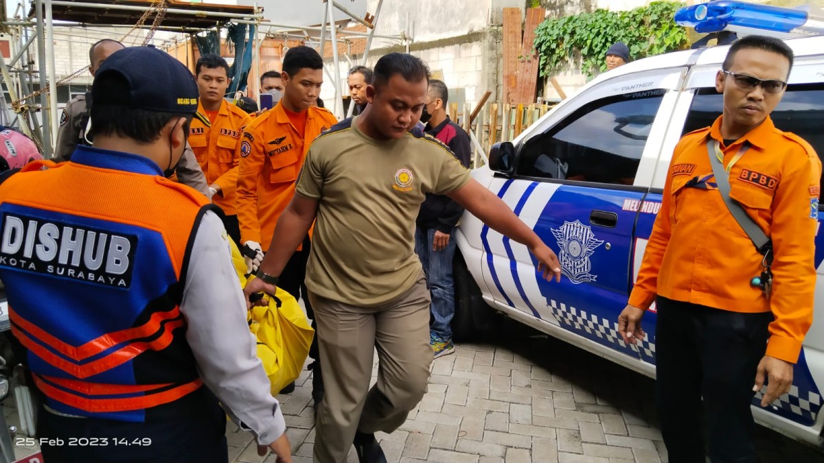 Petugas gabungan mengevakuasi pria asal Jombang yang gantung diri di kamar kos, Jalan Menur Pumpungan Surabaya. (foto: Ari for jatimnow.com)