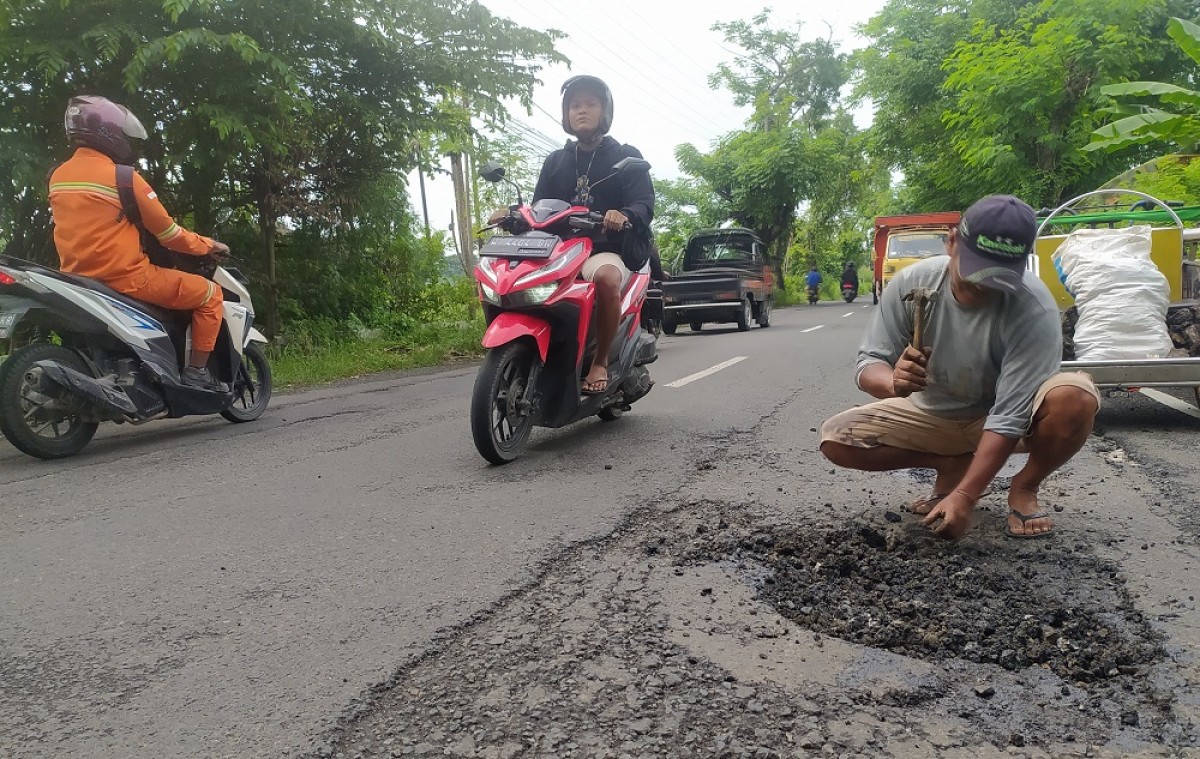 Gufron saat melakukan perbaikan jalan seorang diri di jalan poros Kecamatan Deket - Karangbinangun. (Foto : Adyad Ammy Iffansah/jatimnow.com)