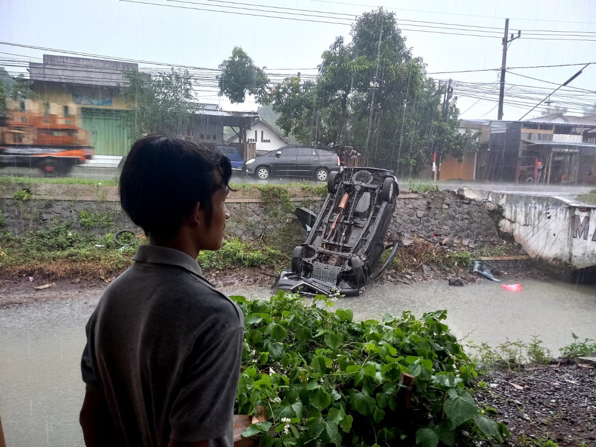 Mobil Avanza nyungsep ke sungai usai menabrak dua motor. (Foto: Elok Aprianto/jatimnow.com)