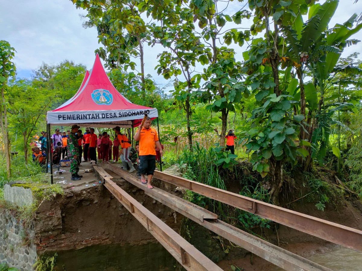 Petugas dan warga memperbaiki jembatan. (Foto-foto: BPBD Jatim for jatimnow.com)
