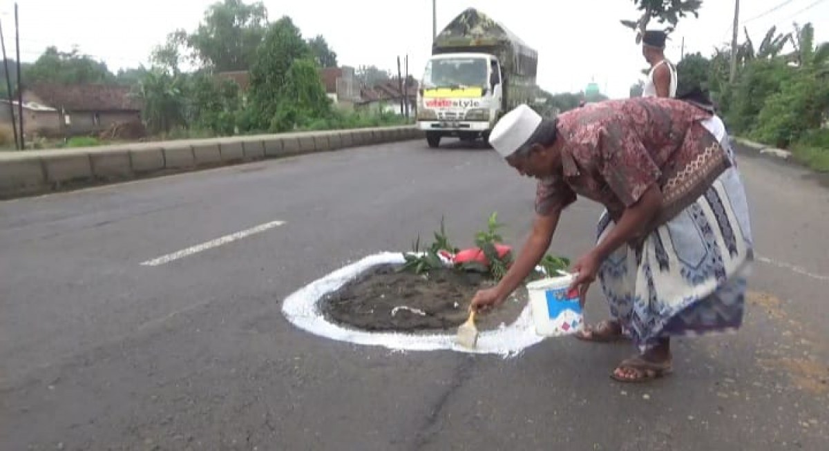 Warga menambal jalan yang berlubang pada jalur Nasional, Jombang-Surabaya. (Foto: Elok Aprianto/jatimnow.com)