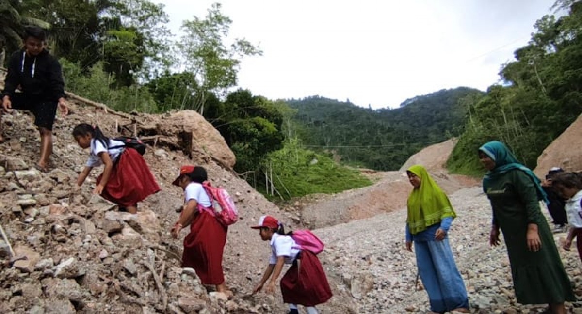 Para siswa berangkat sekolah menantang bahaya lewati material longsor. (Foto: Doyok for jatimnow.com)