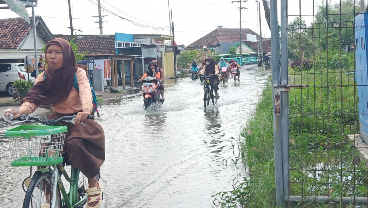 Siswa pulang sekolah saat banjir. (Foto: Zainul Fajar/jatimnow.com)