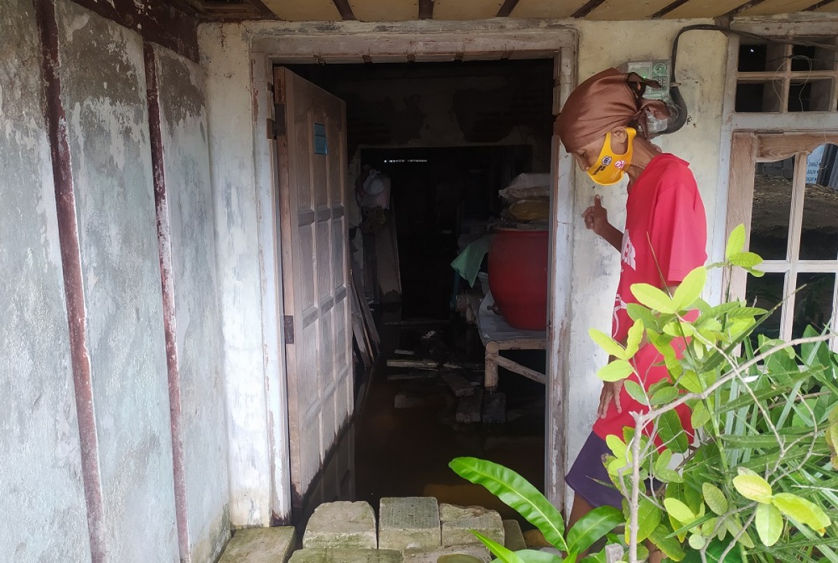 Nenek Sayana saat menunjukan kondisi rumah dan dipenuhi air. (Foto: Adyad Ammy Iffansah/jatimnow.com)   