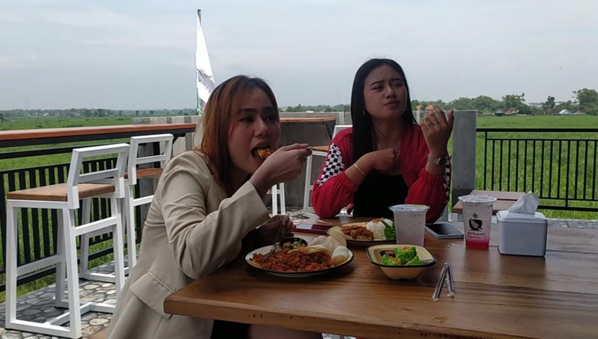 Pengunjung Kafe and Resto Pari Sawah menyantap menu andalan sembari menikmati suasana alam khas pedesaan. (Foto: Elok Aprianto/jatimnow.com)